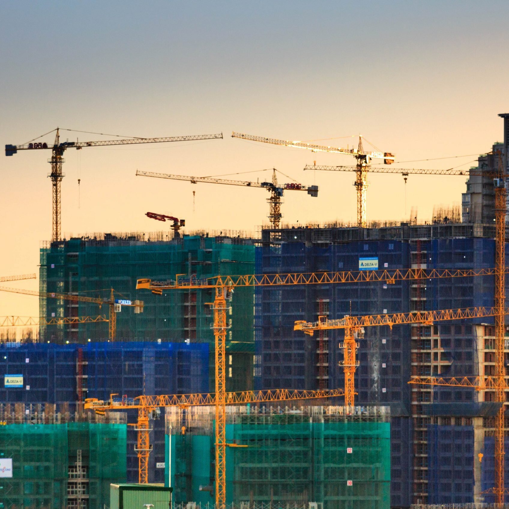Construction site at sunset with multiple cranes and high-rise buildings under construction. - Supply Chain Transparency