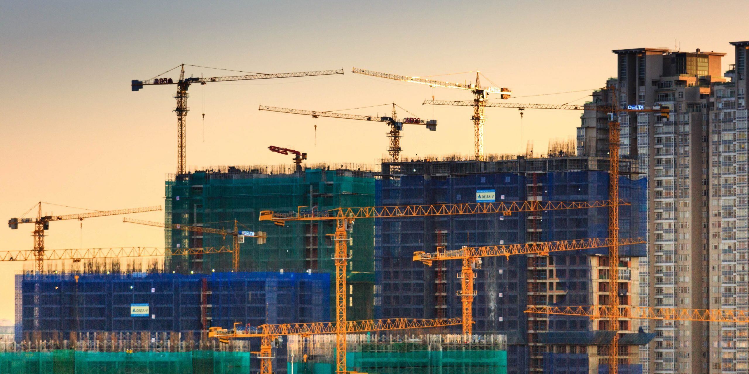 Construction site at sunset with multiple cranes and high-rise buildings under construction. - Supply Chain Transparency