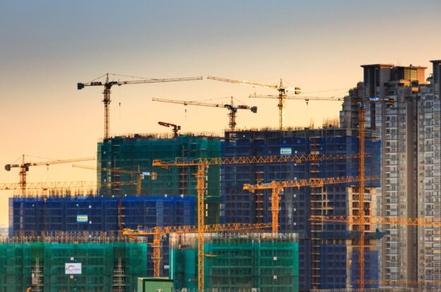 Construction site at sunset with multiple cranes and high-rise buildings under construction. - Supply Chain Transparency