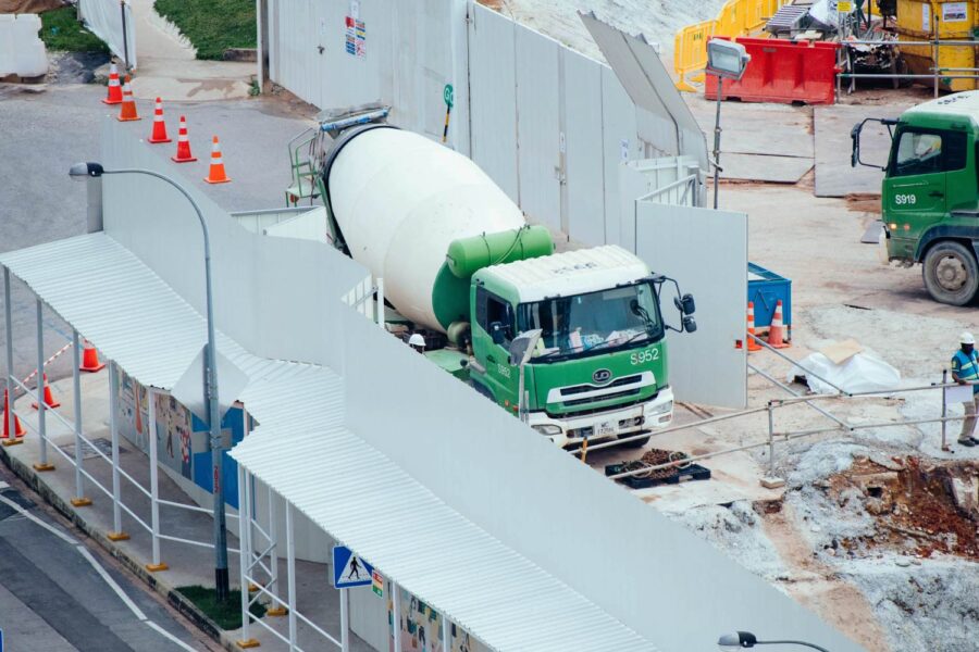Green cement mixer truck at a construction site. License plate S952. - Supply Chain Transparency