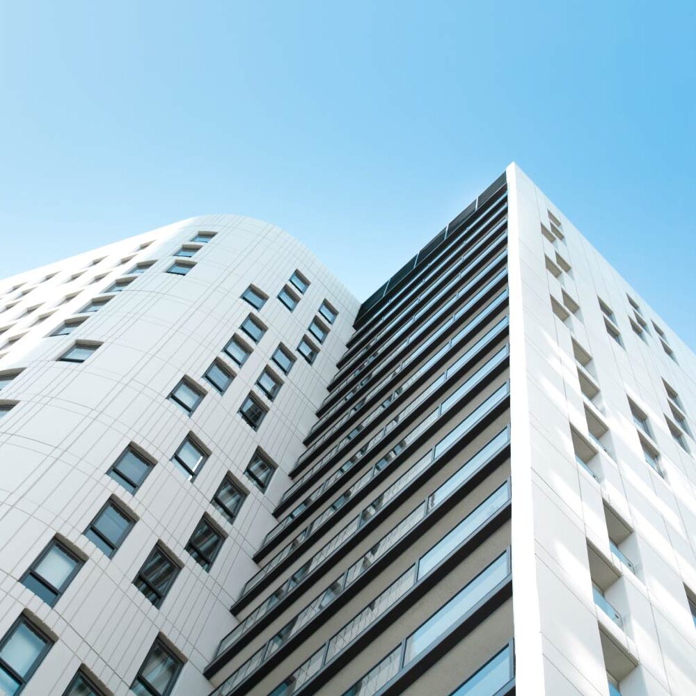 Modern white apartment building with balconies against a blue sky. - Supply Chain Transparency