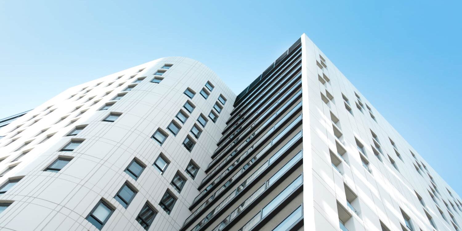 Modern white apartment building with balconies against a blue sky. - Supply Chain Transparency