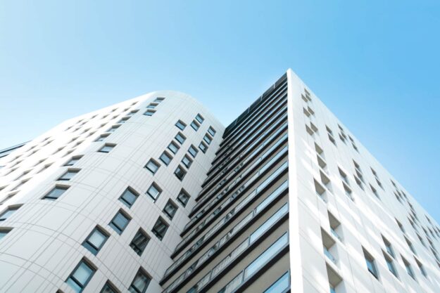 Modern white apartment building with balconies against a blue sky. - Supply Chain Transparency