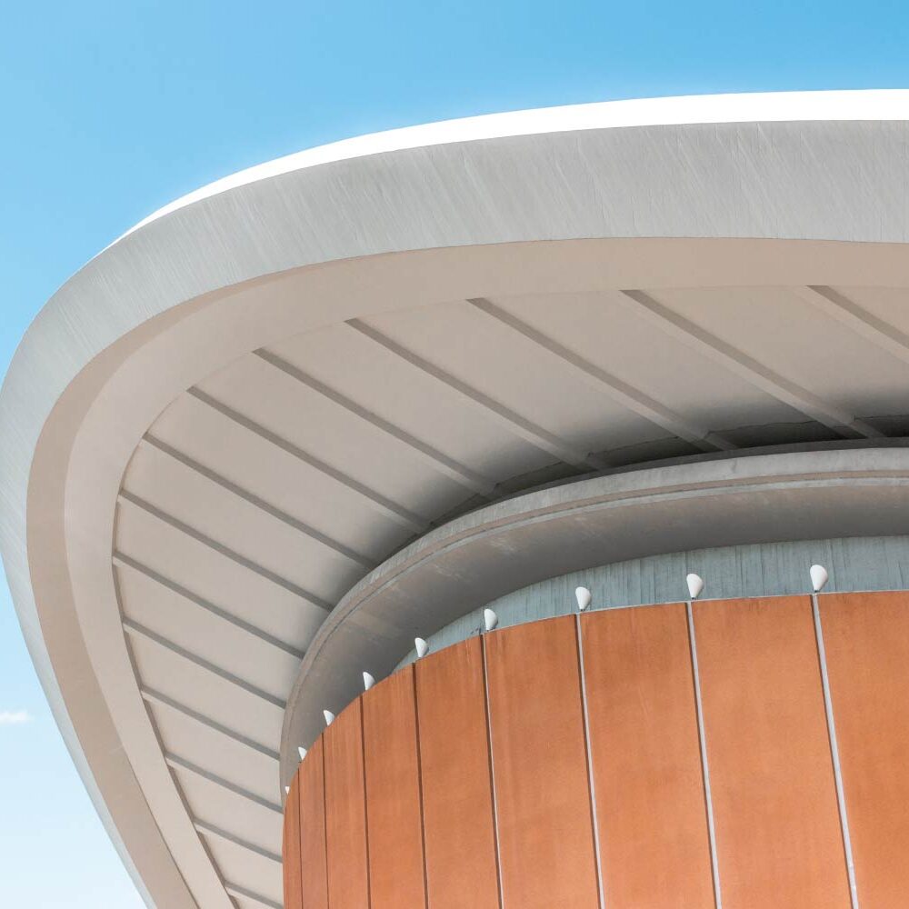 Modern building's curved roof and orange facade against a blue sky. - Supply Chain Transparency