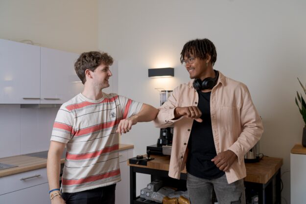 Engaging Stakeholders: Communicating Supply Chain Transparency Initiatives Two men elbow bumping, practicing social distancing in a kitchen. Communicating supply chain transparency. - Supply Chain Transparency