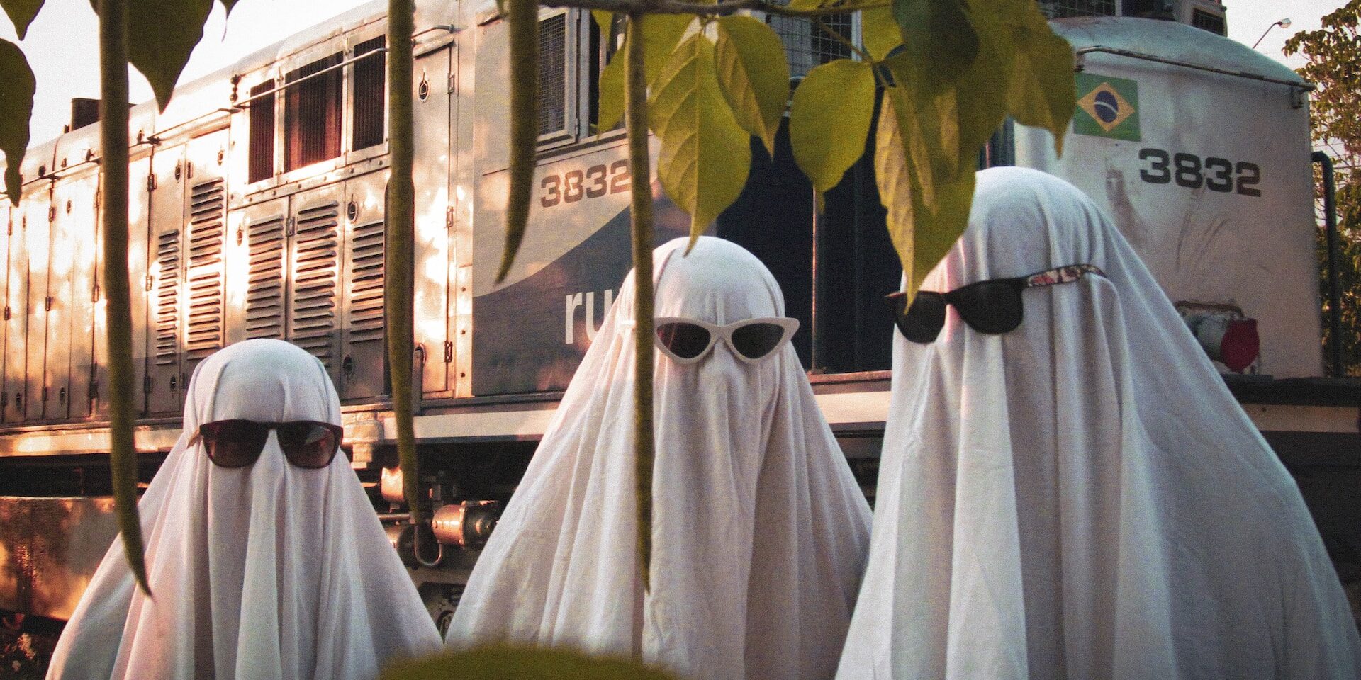 Consumer Demand for Supply Chain Transparency: Trends and Insights Three figures in white sheets and sunglasses stand before a train, illustrating the need for supply chain transparency. - Supply Chain Transparency