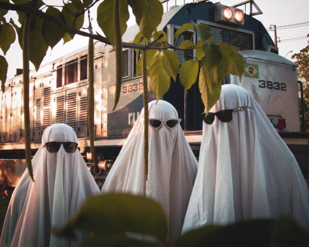 Consumer Demand for Supply Chain Transparency: Trends and Insights Three figures in white sheets and sunglasses stand before a train, illustrating the need for supply chain transparency. - Supply Chain Transparency