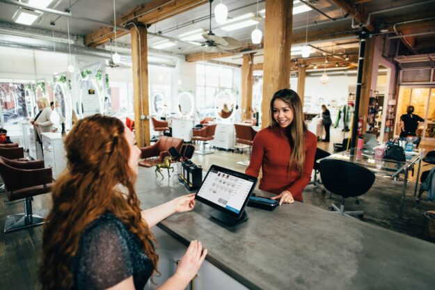 SMEs in International Trade: Opportunities and Challenges Two women at a salon checkout using a tablet for a transaction. - Supply Chain Transparency