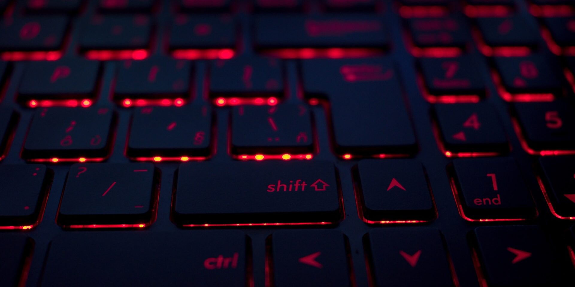 Close-up of a backlit keyboard with the "shift" key highlighted; red backlighting suggests a cybersecurity or fraud detection context. - Supply Chain Transparency
