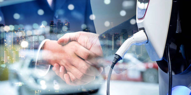 The Power of Collaboration in Supply Chain Innovation Business handshake with electric vehicle charging station; collaboration in supply chain innovation. - Supply Chain Transparency