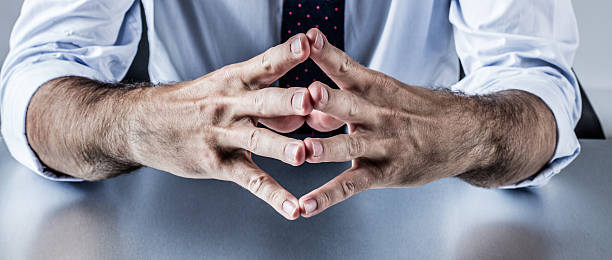 The Human Element: Addressing Employee-Related Fraud in Supply Chains Close-up of hands clasped together, suggesting contemplation or decision-making. Relates to employee fraud in supply chains. - Supply Chain Transparency