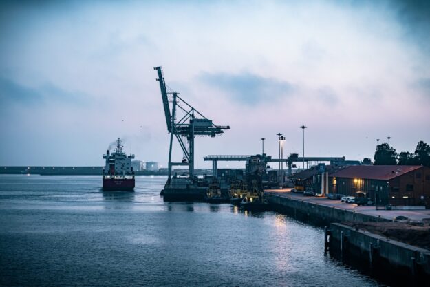 Supply Chains in International Trade: Challenges and Strategies Cargo ship at port with cranes during twilight. Illustrates international trade supply chain. - Supply Chain Transparency