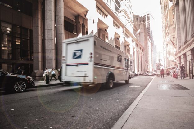 Blurred USPS truck driving down a city street, illustrating supply chain logistics. - Supply Chain Transparency