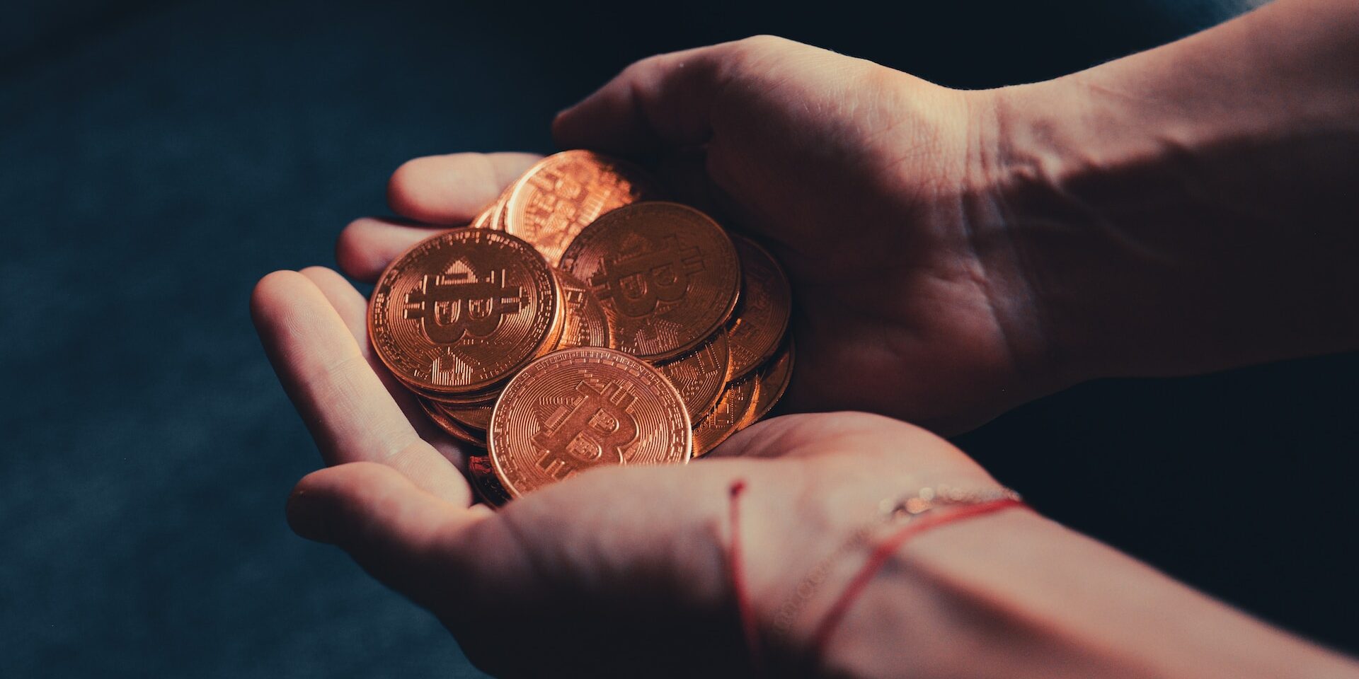 The Impact of Currency Exchange Rates on International Trade Close-up of hands holding a pile of gold Bitcoin coins. - Supply Chain Transparency