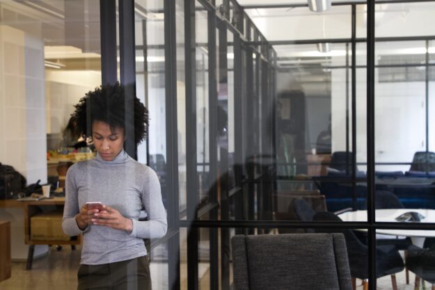 Inside Jobs: Preventing and Detecting Internal Fraud in Supply Chains Woman using smartphone in modern office. Preventing internal fraud. - Supply Chain Transparency