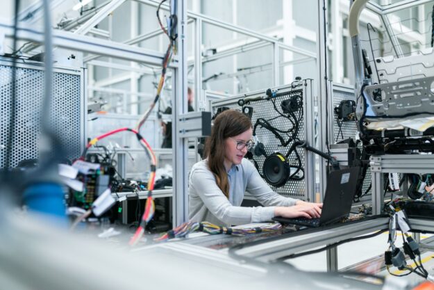 The Role of Artificial Intelligence in Supply Chain Optimization Female engineer using laptop in a modern factory setting, showcasing AI's role in supply chain optimization. - Supply Chain Transparency