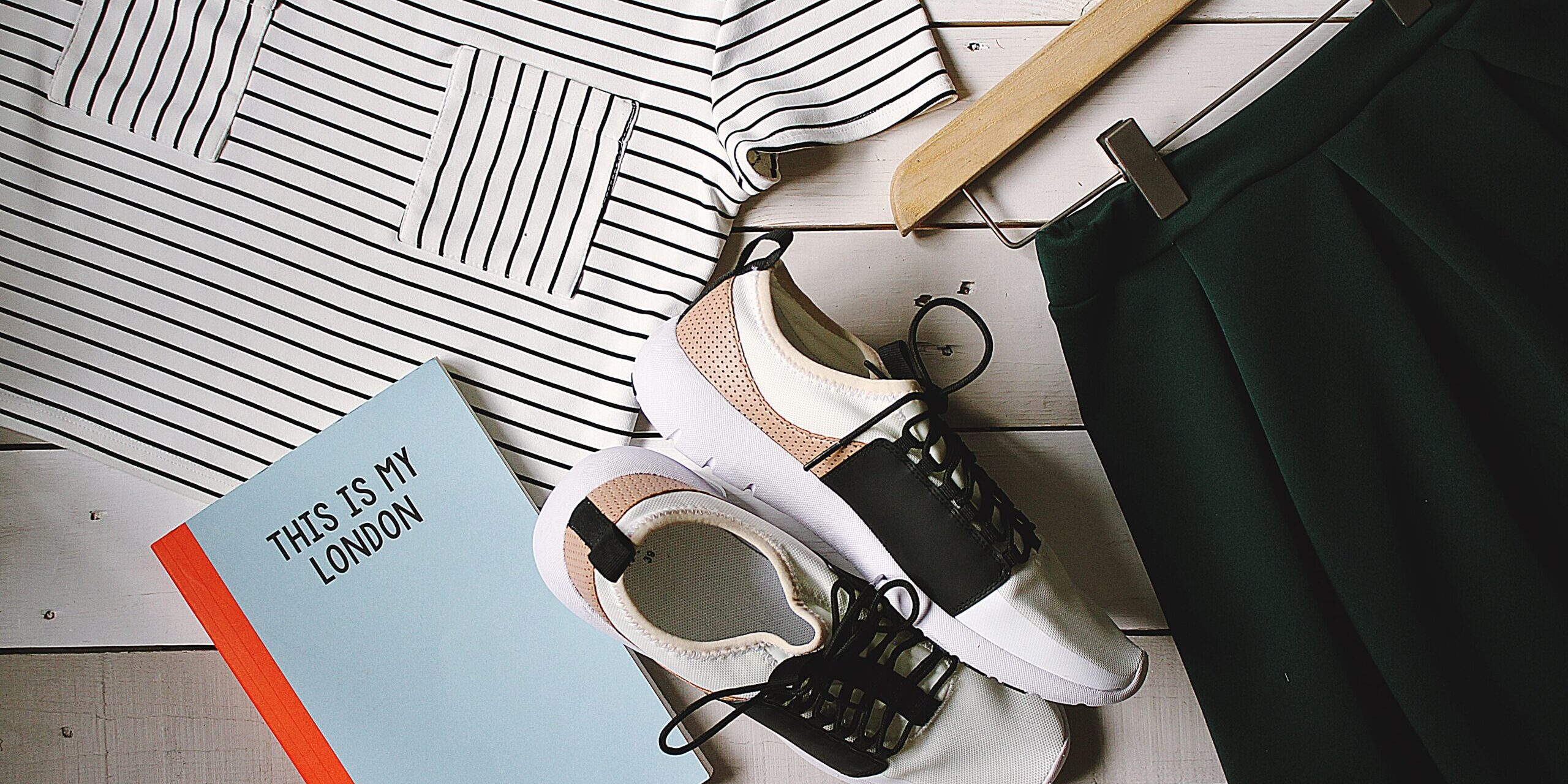 Supply Chain Transparency in the Fashion Industry: Towards Sustainable Practices Flatlay of striped shirt, green skirt, sneakers, and "This Is My London" book. Illustrates sustainable fashion. - Supply Chain Transparency
