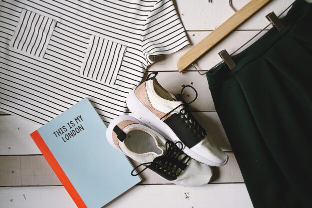 Supply Chain Transparency in the Fashion Industry: Towards Sustainable Practices Flatlay of striped shirt, green skirt, sneakers, and "This Is My London" book. Illustrates sustainable fashion. - Supply Chain Transparency