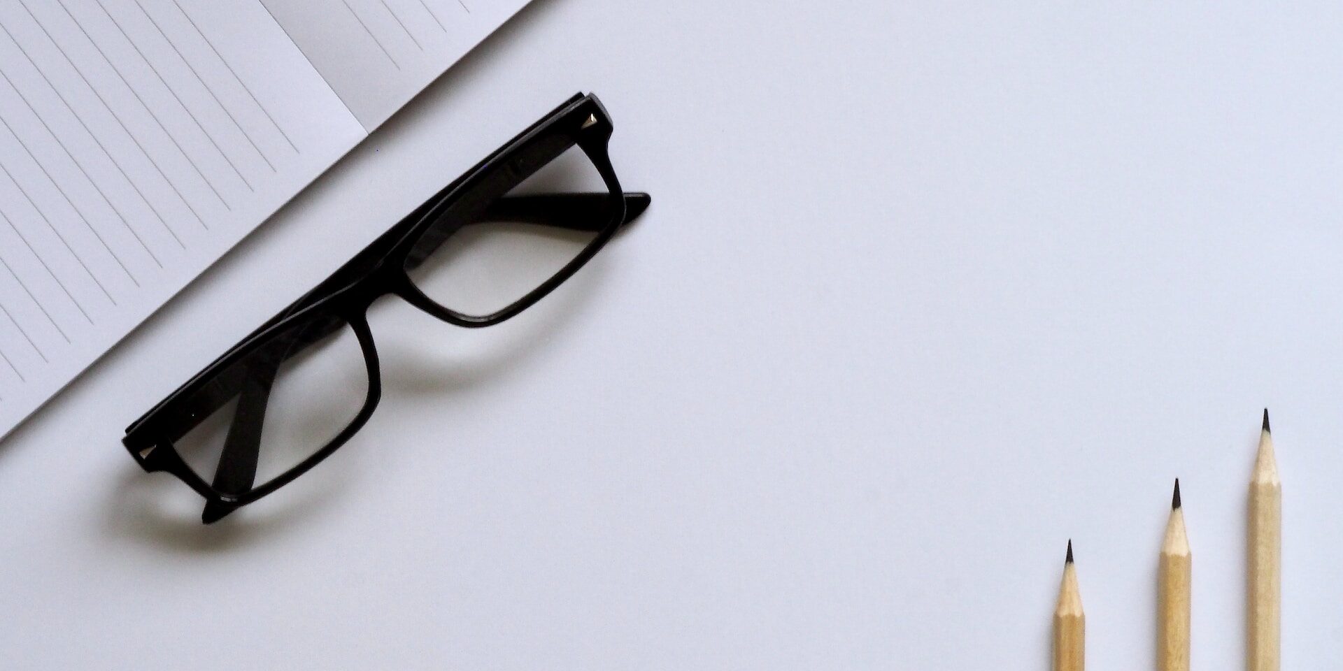Notepad, eyeglasses, and pencils on a white desk. Ethical supply chain concept. - Supply Chain Transparency
