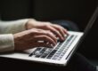 Person's hands typing on a laptop, illustrating technology's role in streamlining supply chains. - Supply Chain Transparency