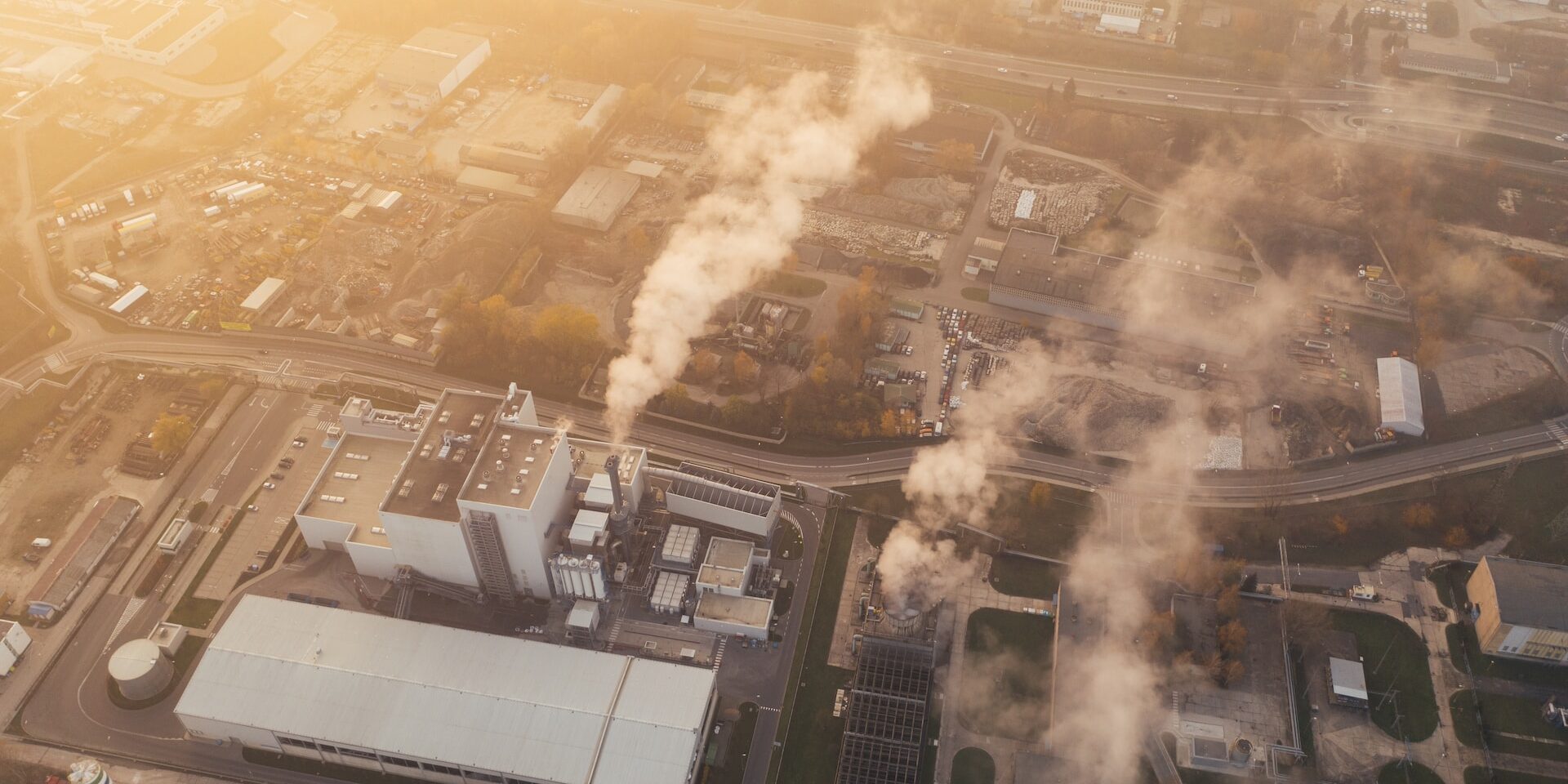 Aerial view of industrial plant emitting smoke, illustrating climate change's impact on global supply chains. - Supply Chain Transparency