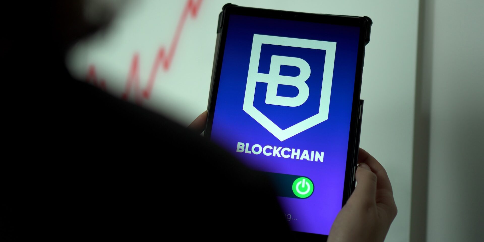 Understanding the Impact of Globalization on Supply Chains Person holding tablet displaying Blockchain logo and power button. Supply chain transparency. - Supply Chain Transparency