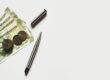 Indian rupees, coins, and pens on a white background. Illustrating supply chain finance. - Supply Chain Transparency
